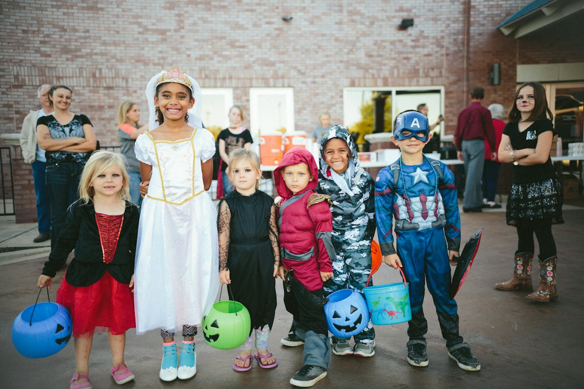 Children in Halloween costumes holding pumpkin buckets