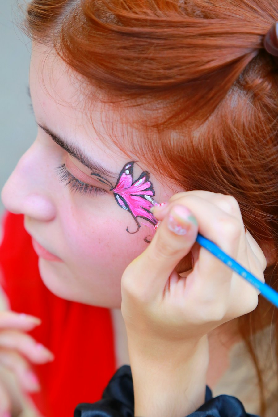 Butterfly being face painted on a girl's cheek