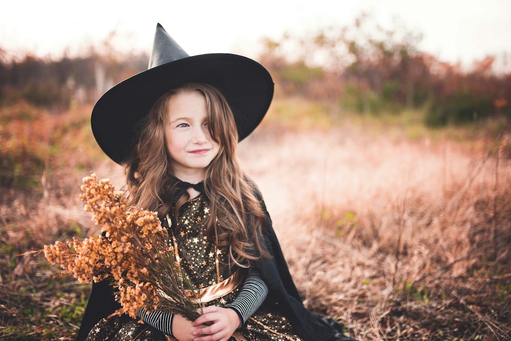 Smiling girl in a witch costume in an autumn field